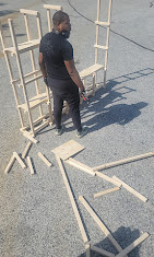 Crew member disassembling wooden shelving units into flat pieces before loading