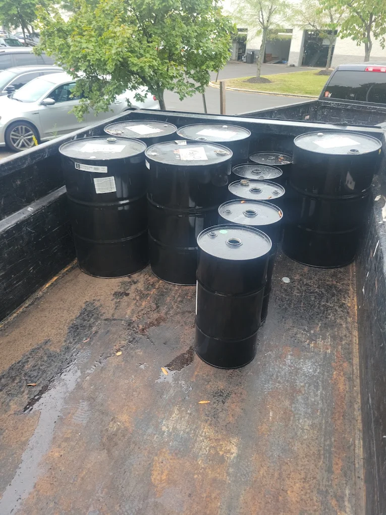 Steel drums loaded into a Baten dump trailer for commercial disposal