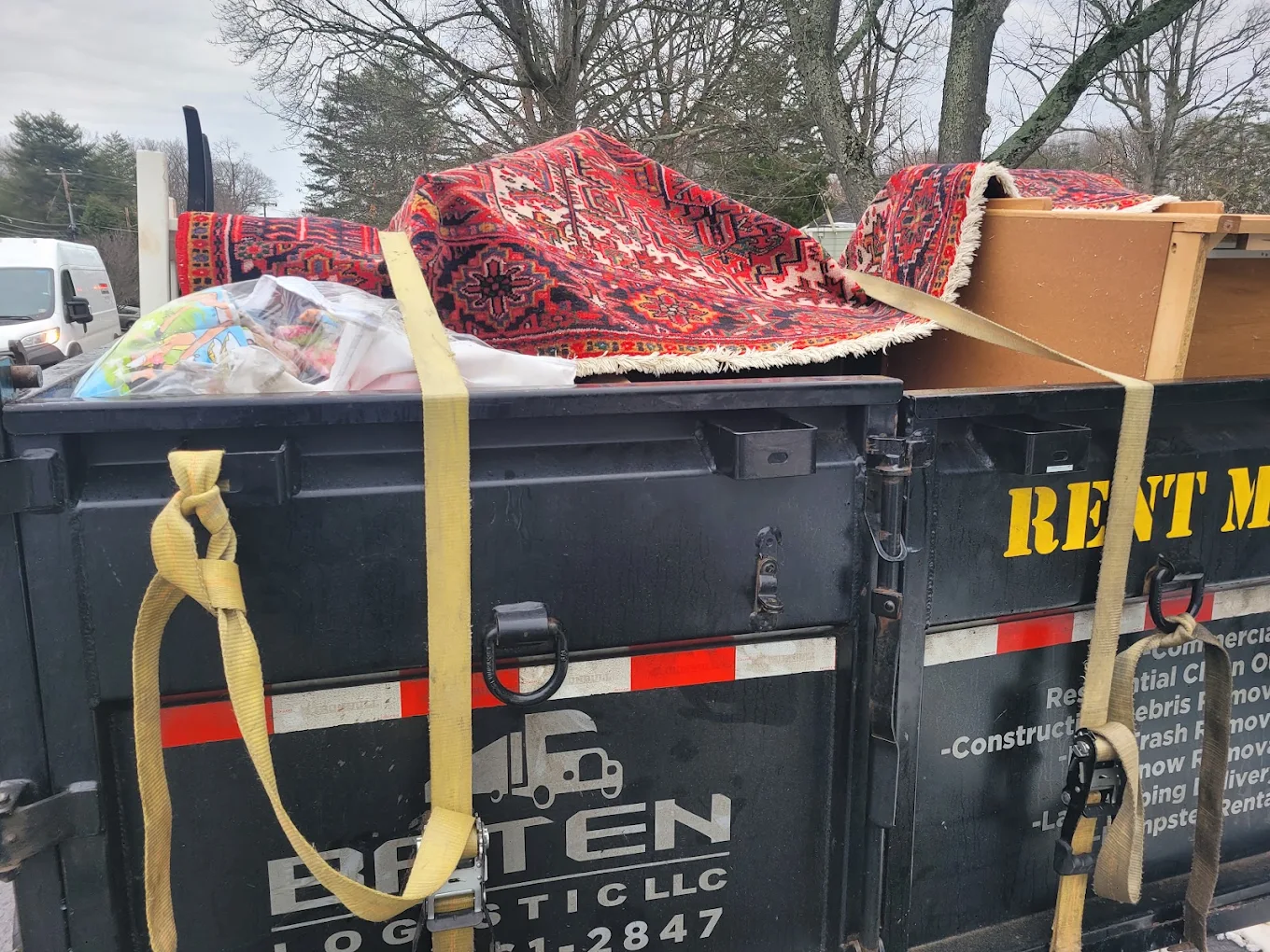 Baten Logistic dumpster strapped and loaded with rugs, furniture and household goods