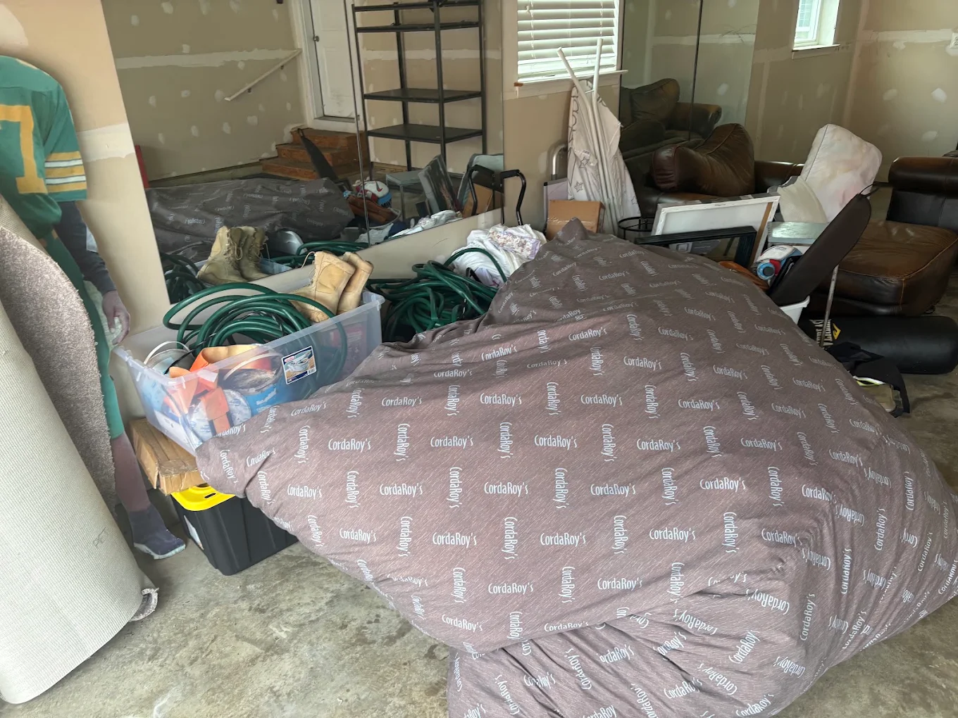 Two-car garage packed with furniture, bins, hoses and a bean bag before a Baten cleanout