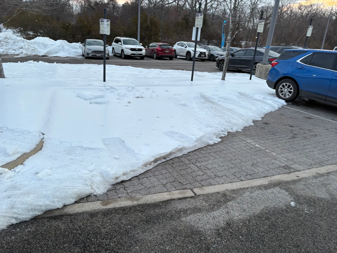 Snow-covered commercial parking lot at dusk cleared back to pavement by the Baten crew