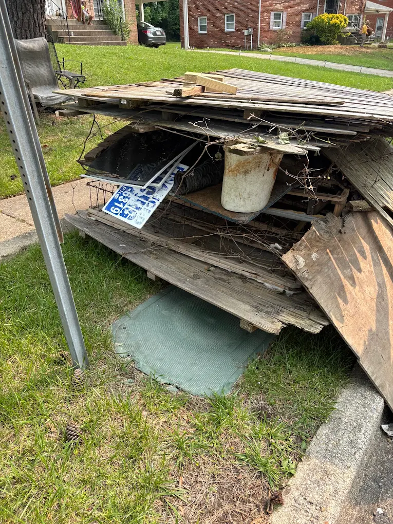 Old deck boards, fencing and lattice stacked at the curb in front of a brick apartment building for pickup