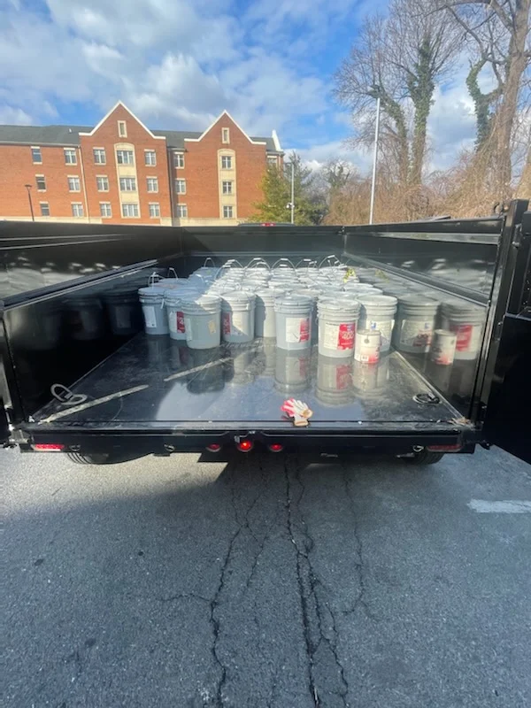Dump trailer bed lined with dozens of five-gallon buckets on a campus job