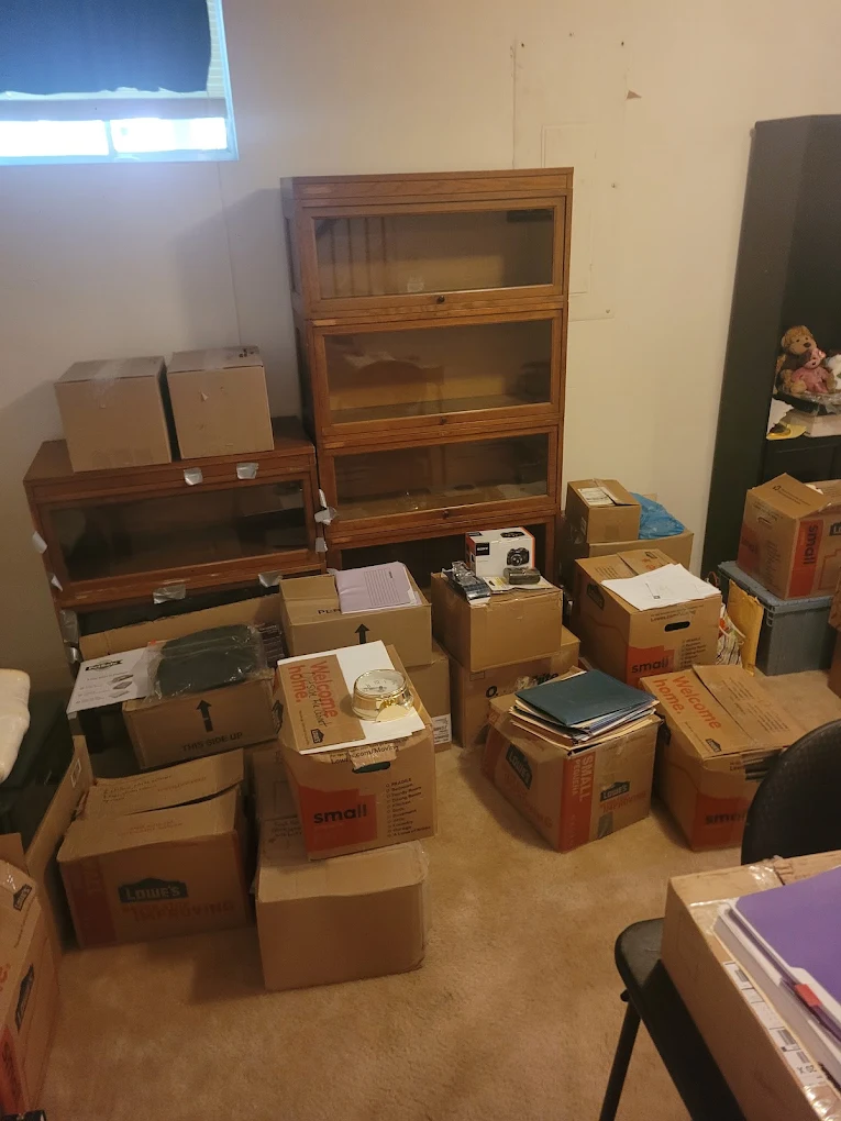 Basement room filled with moving boxes, barrister bookcases and files before a downsizing cleanout