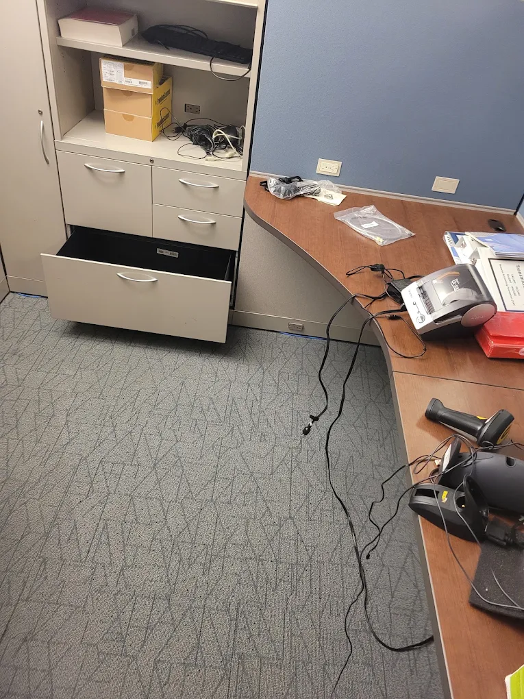 Office workstation mid-decommission with an open filing cabinet, loose cabling and scanners on the desk
