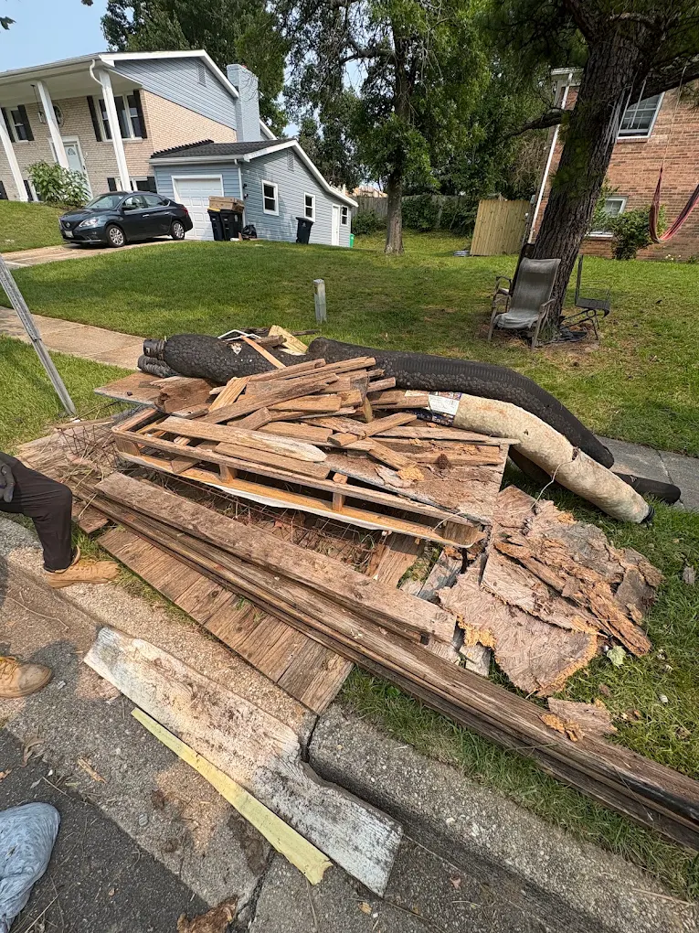 Demolished deck lumber, boards and a pool liner piled at the curb after a backyard teardown