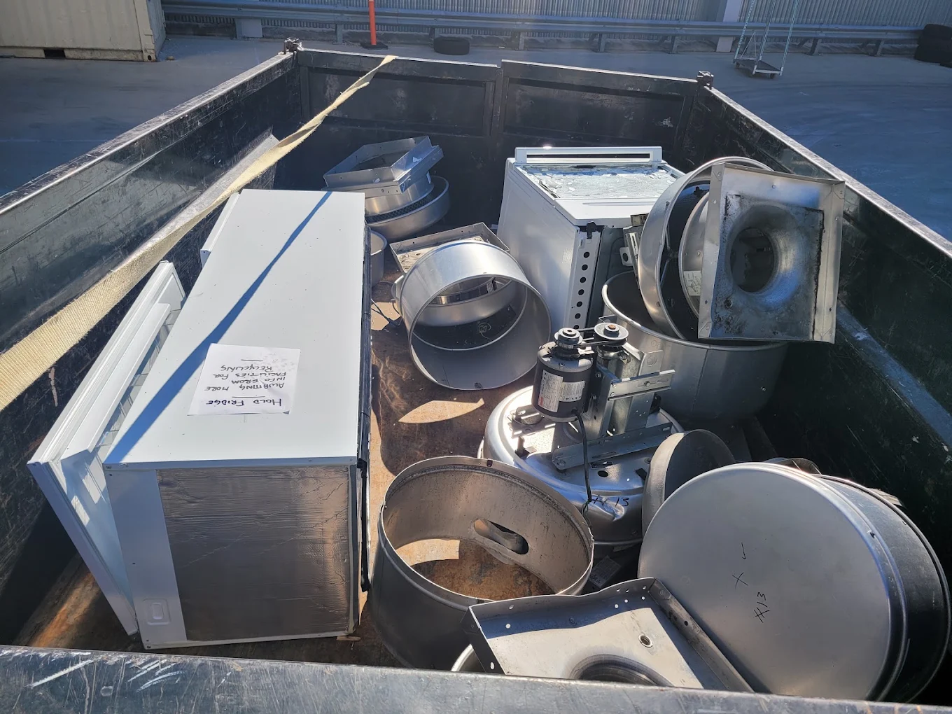 Dump trailer loaded with HVAC ductwork, blower housings and an old fridge sorted for metal recycling