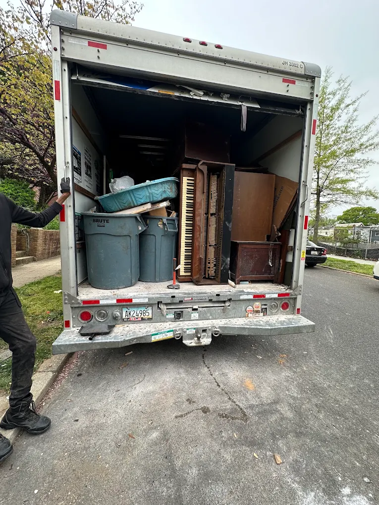 Box truck loaded with an upright piano, dressers, bins and a mattress on a residential street