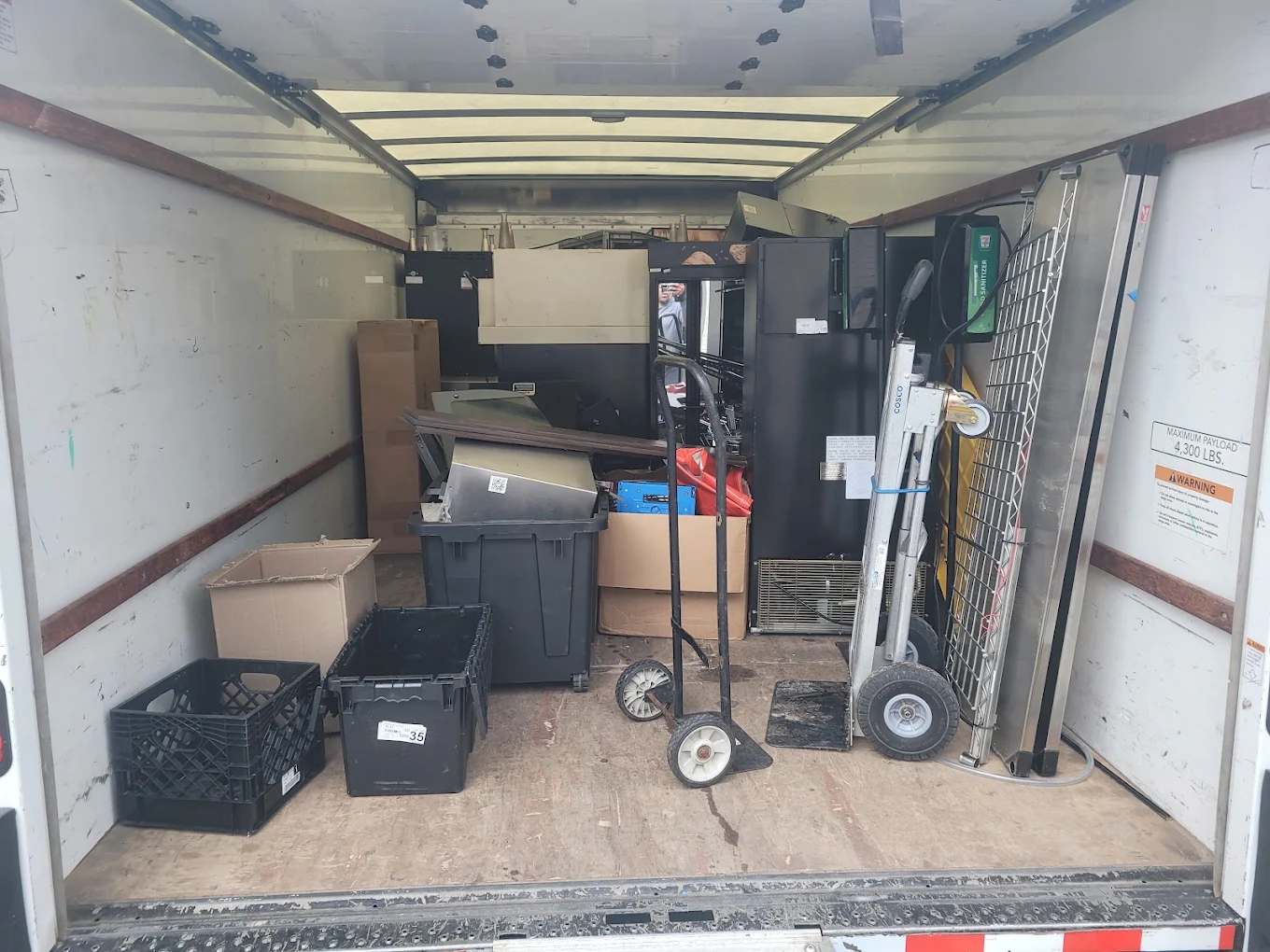 Box truck interior loaded with office furniture, filing cabinets, bins and hand trucks