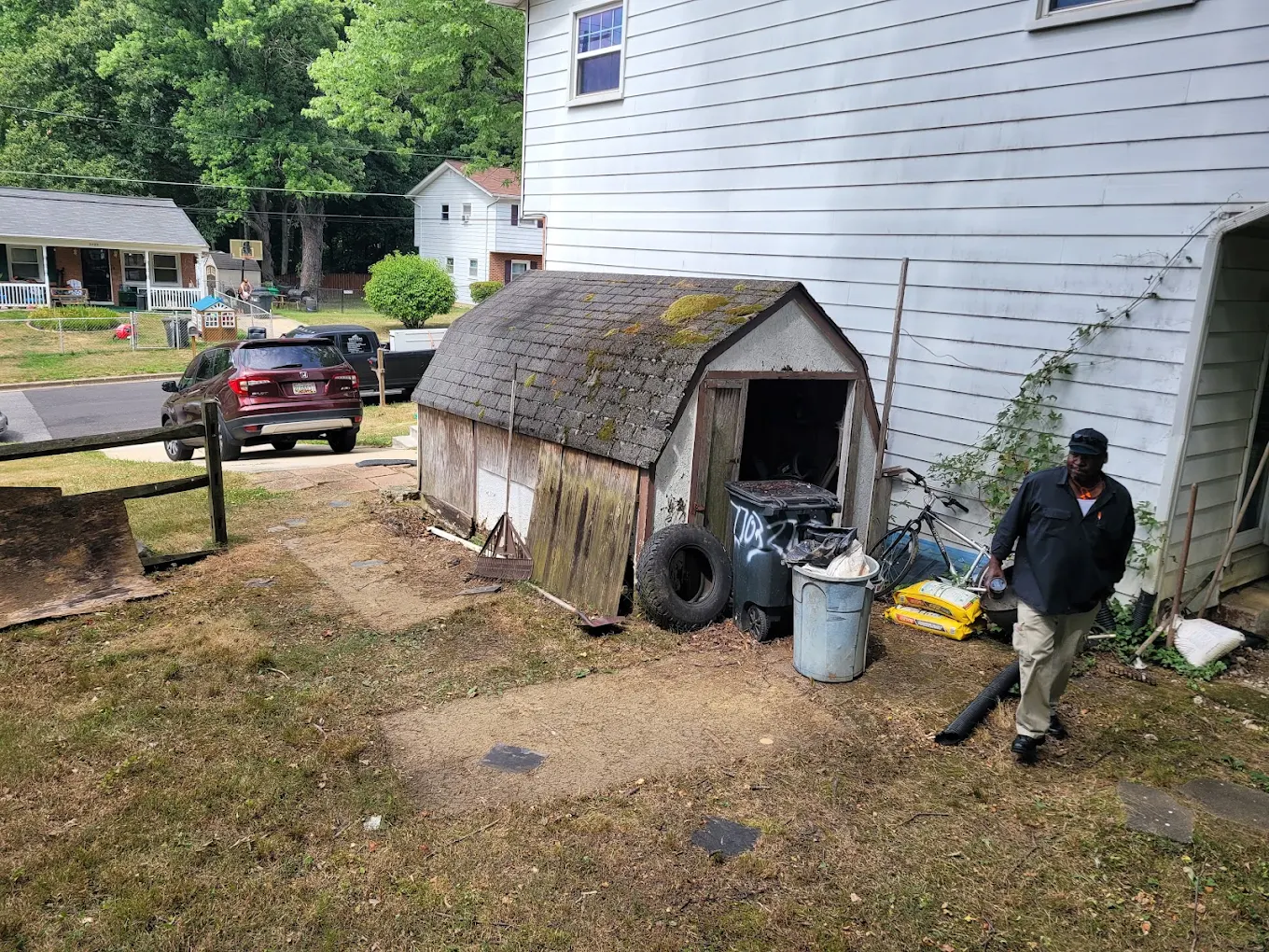 Mario Baten clearing a backyard around an old shed with cans, tires and yard debris