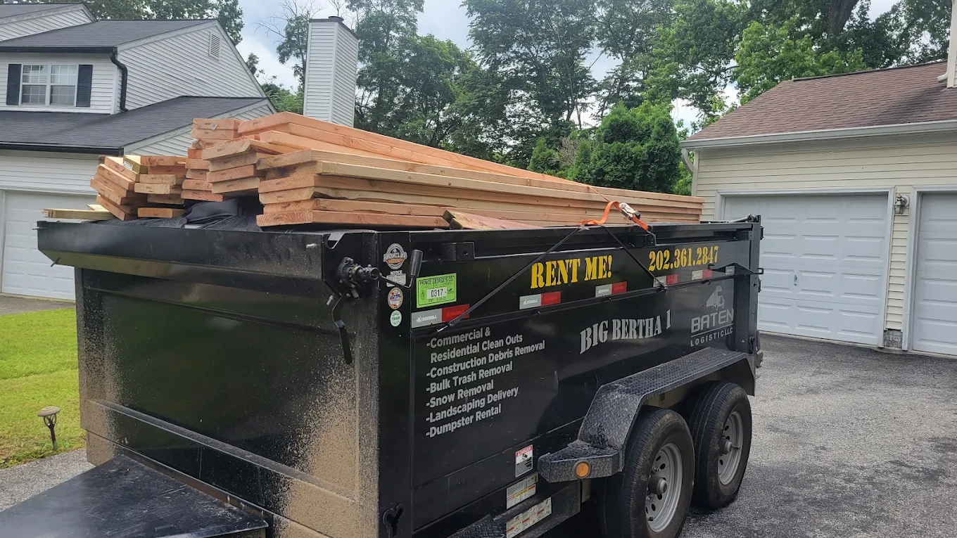 Big Bertha 1 dumpster trailer loaded with fresh lumber in a residential driveway