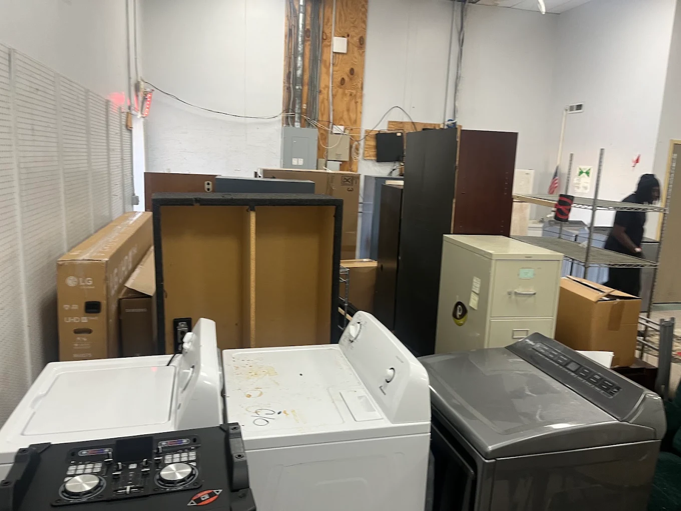 Warehouse staging area with washers, dryers, file cabinets and boxed electronics ready for haul-off