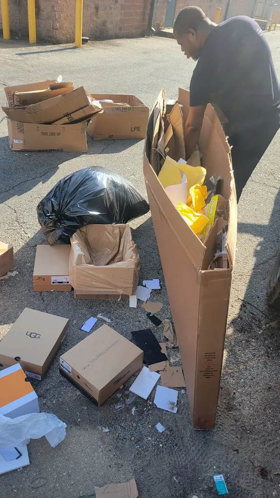 Baten crew member breaking down cardboard boxes and packaging in a commercial lot