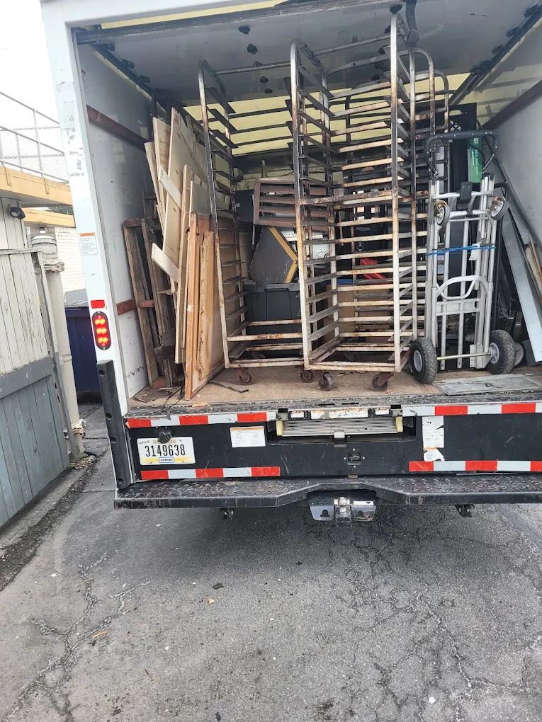 Box truck loaded with commercial bakery racks, shelving and hand trucks in a back alley
