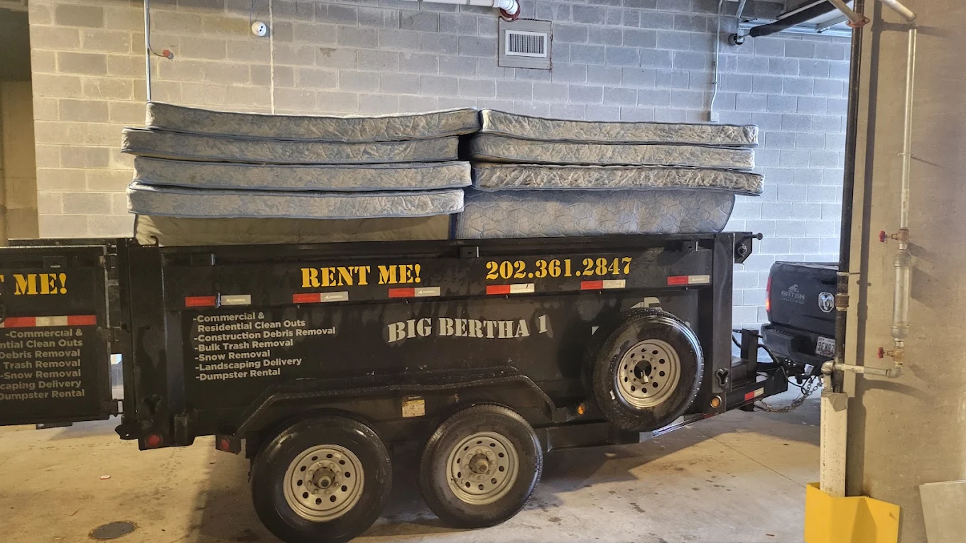 Big Bertha 1 dump trailer stacked with six mattresses inside a parking garage next to the Baten Ram truck