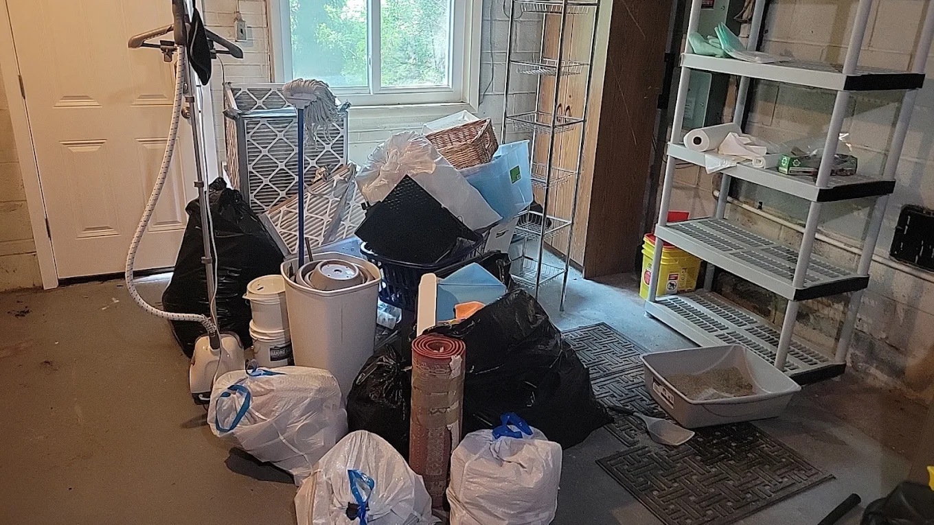 Garage staged with bagged junk, shelving, filters and a rolled rug ready for removal