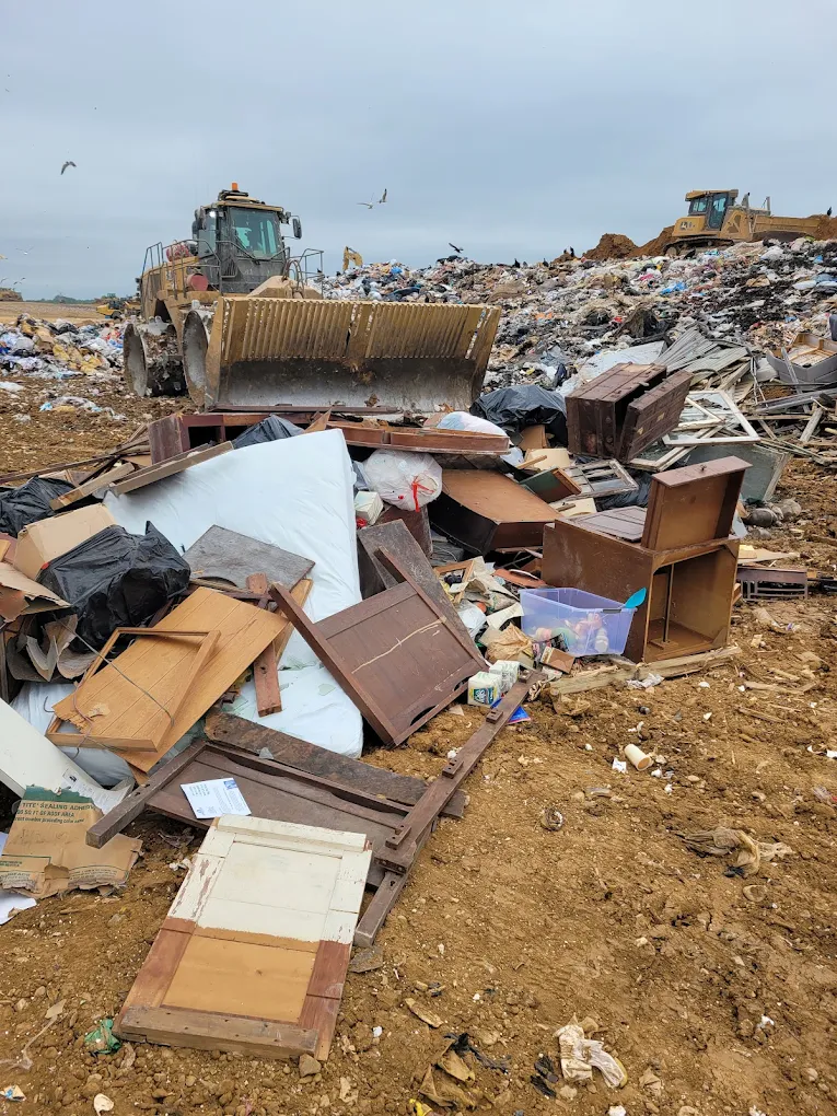 Working landfill face with dozers pushing furniture and construction debris
